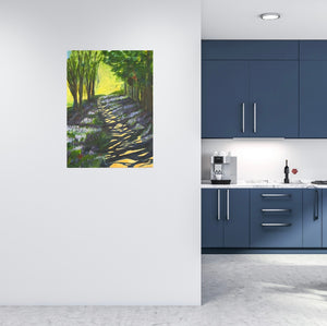 A tree lined path showing the sun peeping through the trees, leaving a shadowy light on the ground.  Bright sunlight and crop filled trees can be seen in distance.  Room mock-up of the blue kitchen with the painting on a pale wall - making the bluebells pop in the painting.