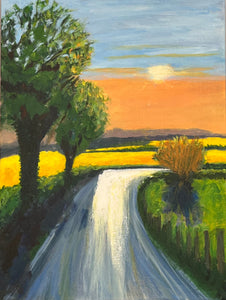 Image of a tree lined country road leading to bright yellow crop filled fields and a golden sunset beyond.  