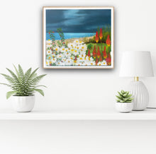 Load image into Gallery viewer, A framed version on a wall.  A seaside floral painting - Bettystown, Ireland.  A bed of daisies and red poker flowers are seen the the foreground with the sea and sky beyond.    