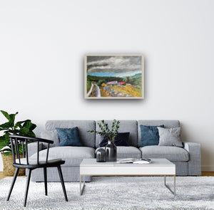 Image of painting framed in a room setting with a grey sofa. Painting on wall above. 