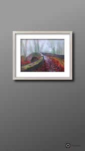Room setting with silver white frame on wall with the Oldbridge canal bridge in foreground with fallen autumn leaves on ground.  Bare ivy covered trees in background.  art for sale  gift ideas