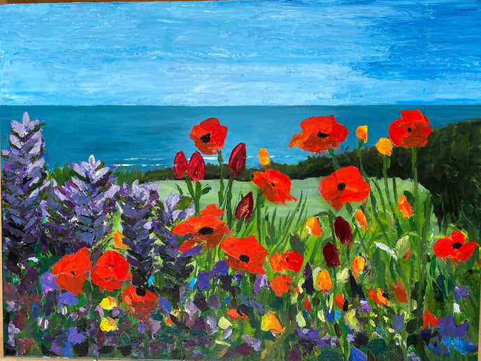 Red poppies and purple lupins in the foreground with a green lawn and hedgerow behind.  The blue sea in the distance below a light blue summery sky.  Seaside floral acrylic painting.  art for sale and gift ideas  Ireland